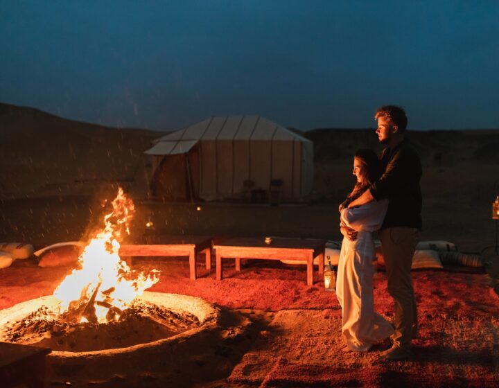 Couple hug in love near big campfire. Romantic night in glamping desert camp in Sahara, Morocco